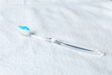 Photo of One toothbrush with toothpaste on white towel