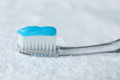 Photo of Toothbrush with toothpaste on white towel, closeup