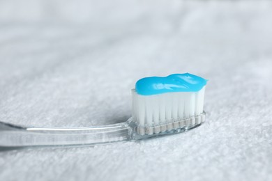 Photo of Toothbrush with toothpaste on white towel, closeup