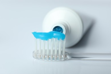 Photo of Toothbrush with toothpaste and tube on white background, closeup