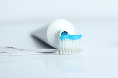 Photo of Toothbrush with toothpaste and tube on white background, closeup