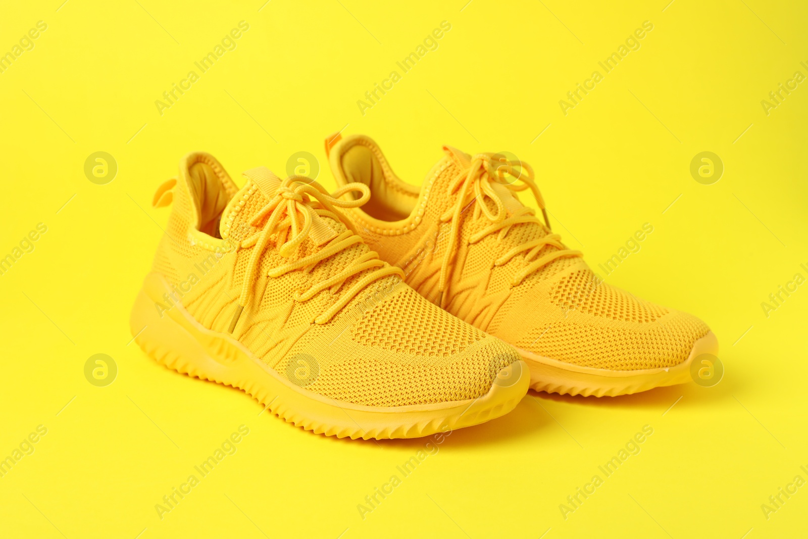 Photo of Pair of stylish sneakers on yellow background