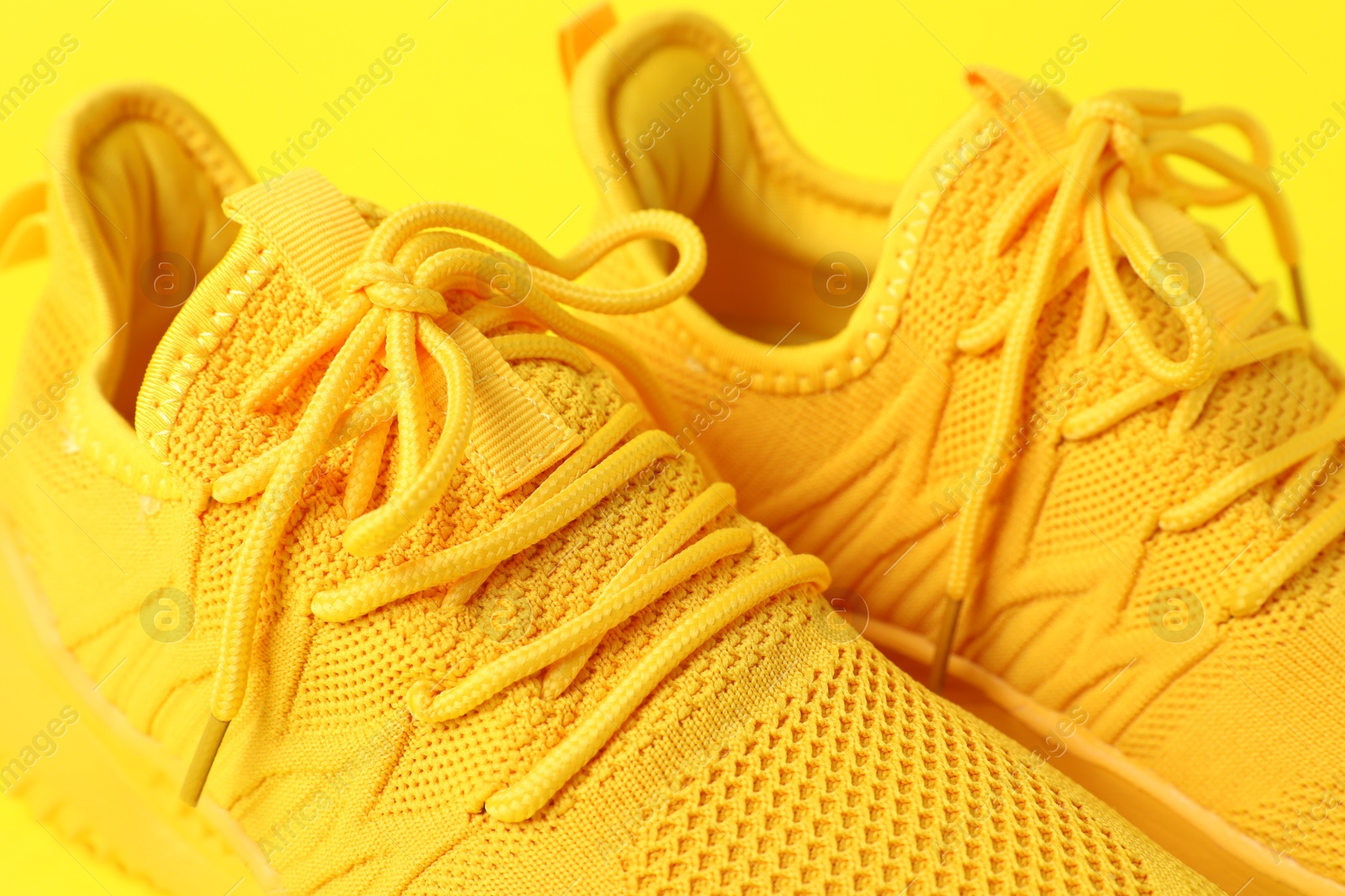 Photo of Pair of stylish sneakers on yellow background, closeup