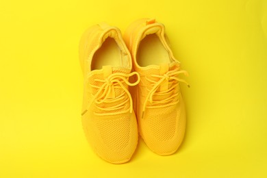 Photo of Pair of stylish sneakers on yellow background, above view