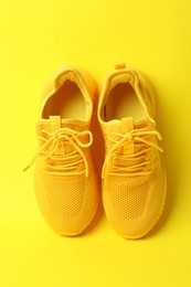 Photo of Pair of stylish sneakers on yellow background, above view