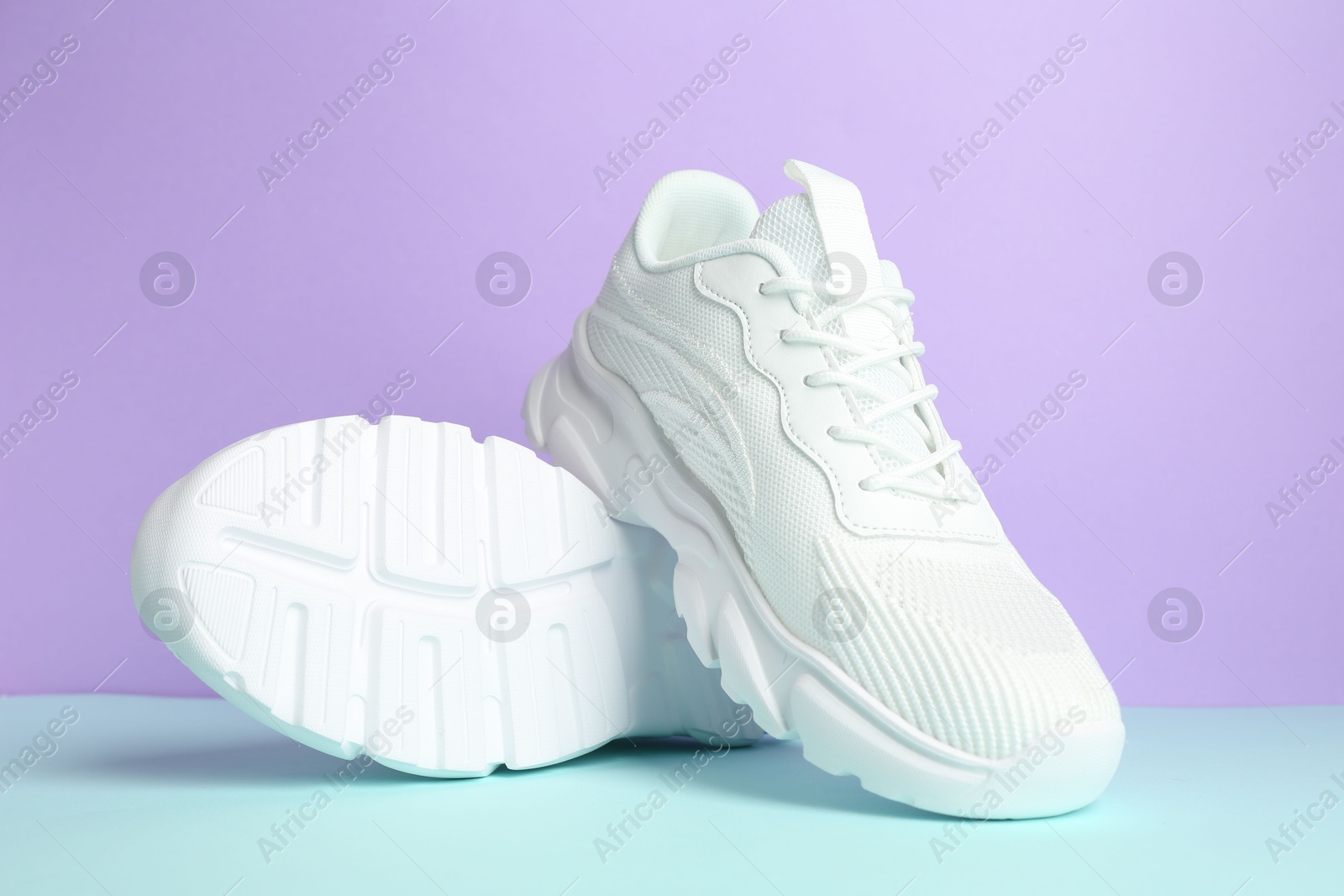 Photo of Pair of stylish white sneakers on color background