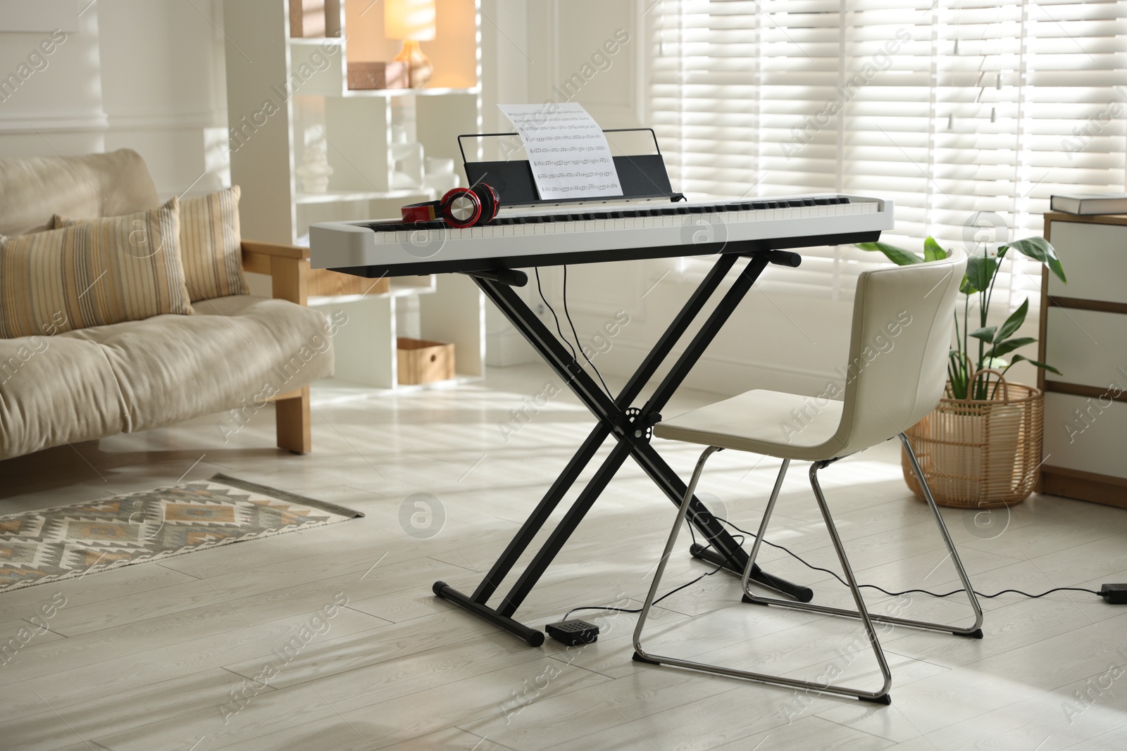 Photo of Synthesizer with music sheet, headphones and chair indoors