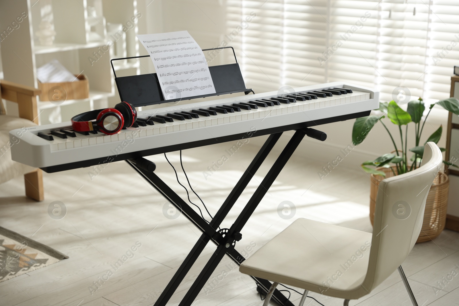 Photo of Synthesizer with music sheet, headphones and chair indoors