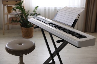 Synthesizer with music sheets and stool indoors