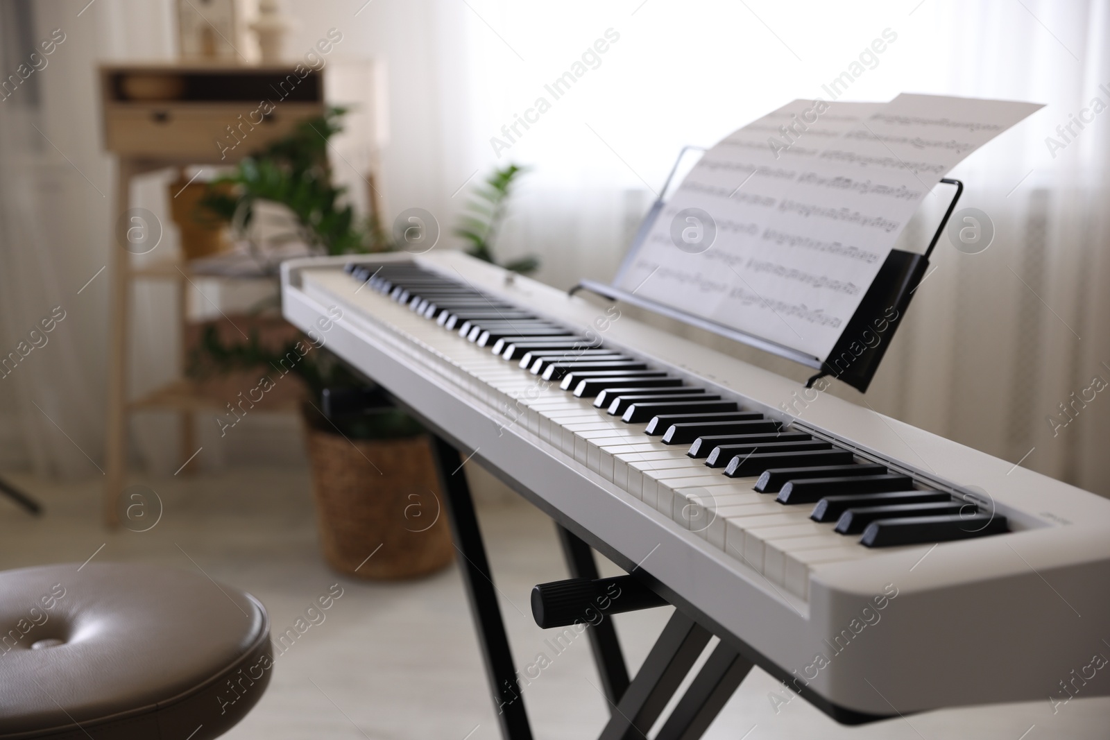 Photo of Synthesizer with music sheets and stool indoors, closeup