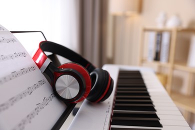 Photo of Synthesizer with music sheet and headphones indoors, closeup