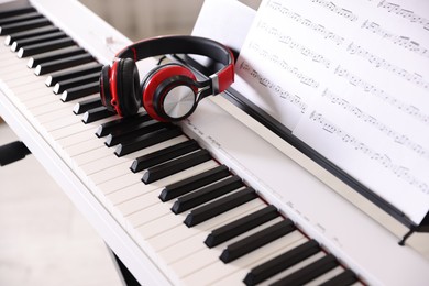 Photo of Synthesizer with music sheets and headphones indoors, closeup