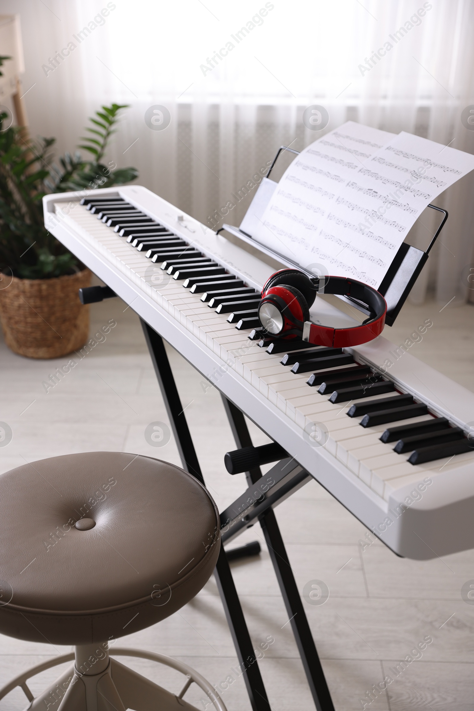 Photo of Synthesizer with music sheets, headphones and stool indoors