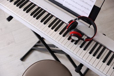 Photo of Synthesizer with music sheets, headphones and stool indoors, above view