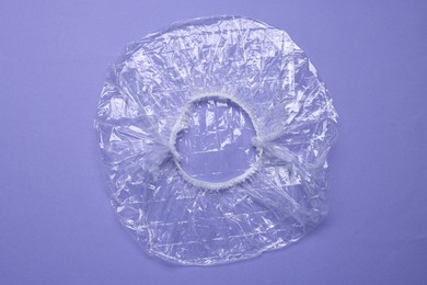 One shower cap on violet background, top view