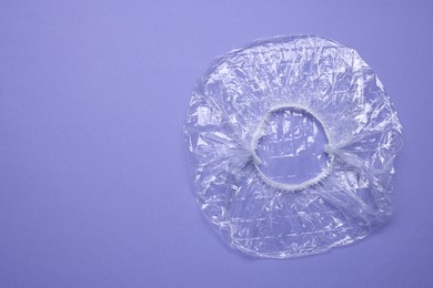 Photo of One shower cap on violet background, top view. Space for text