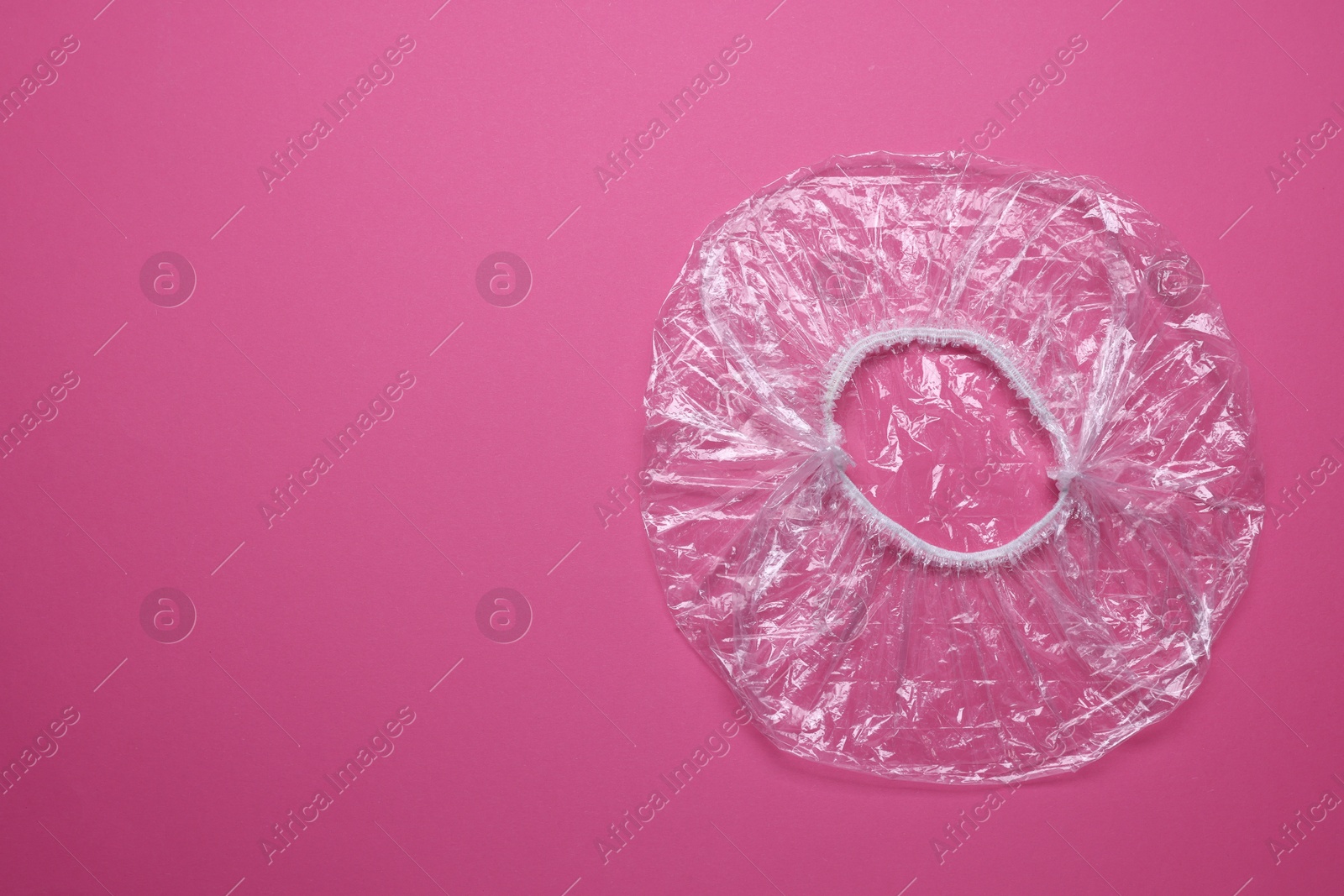 Photo of One shower cap on pink background, top view. Space for text