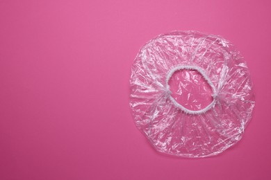 Photo of One shower cap on pink background, top view. Space for text