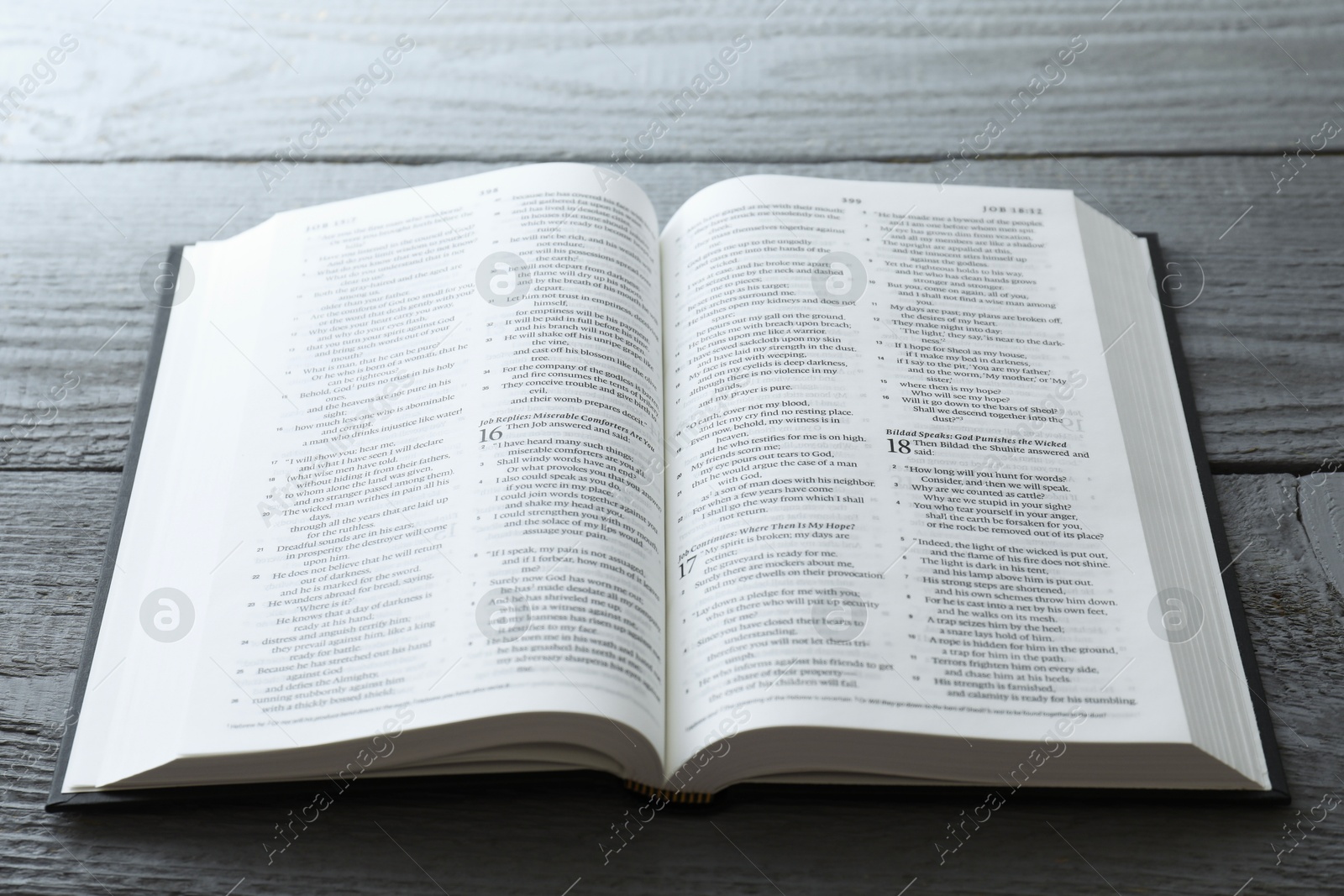 Photo of Open Holy Bible in English language on wooden table