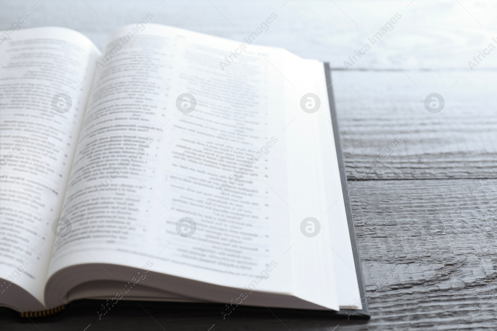 Photo of Open Holy Bible in English language on wooden table, closeup