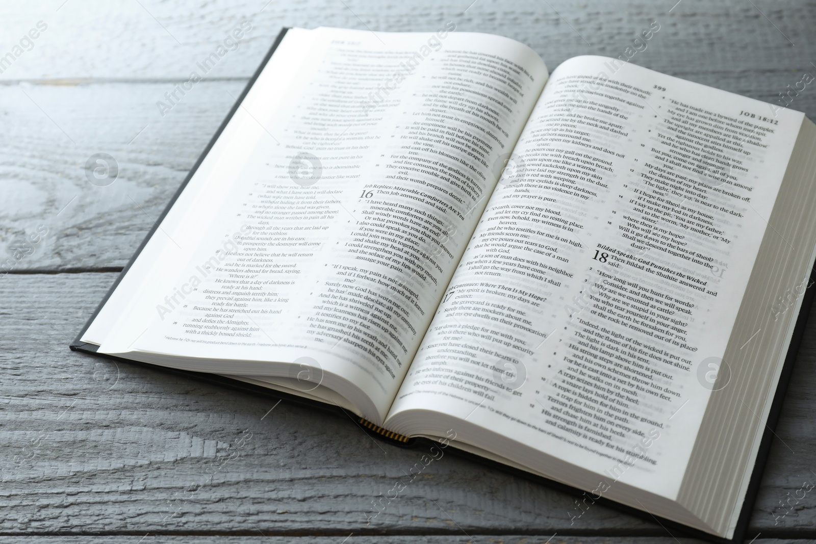 Photo of Open Holy Bible in English language on wooden table