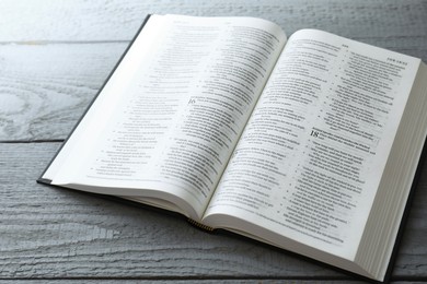 Photo of Open Holy Bible in English language on wooden table