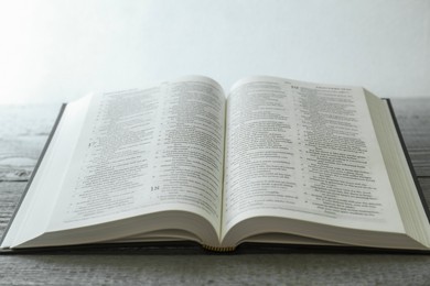 Photo of Open Holy Bible in English language on wooden table, closeup