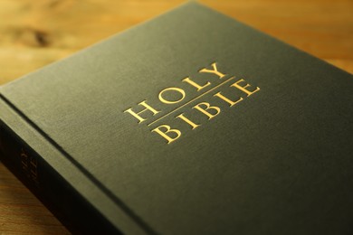 Photo of Hardcover Holy Bible on wooden table, closeup