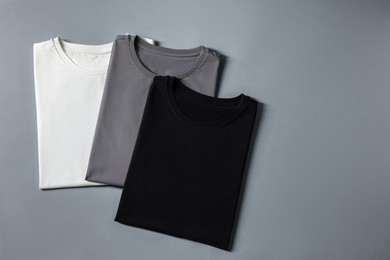 Photo of Different blank t-shirts on grey background, top view. Mockup for design