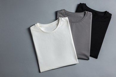 Photo of Different blank t-shirts on grey background, top view. Mockup for design