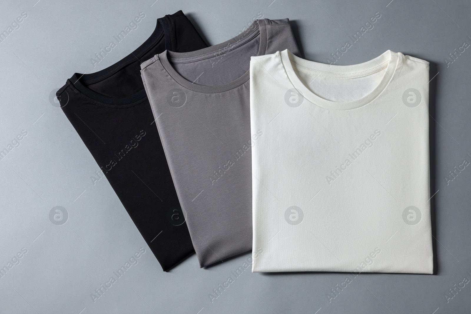 Photo of Different blank t-shirts on grey background, top view. Mockup for design