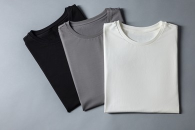 Different blank t-shirts on grey background, top view. Mockup for design