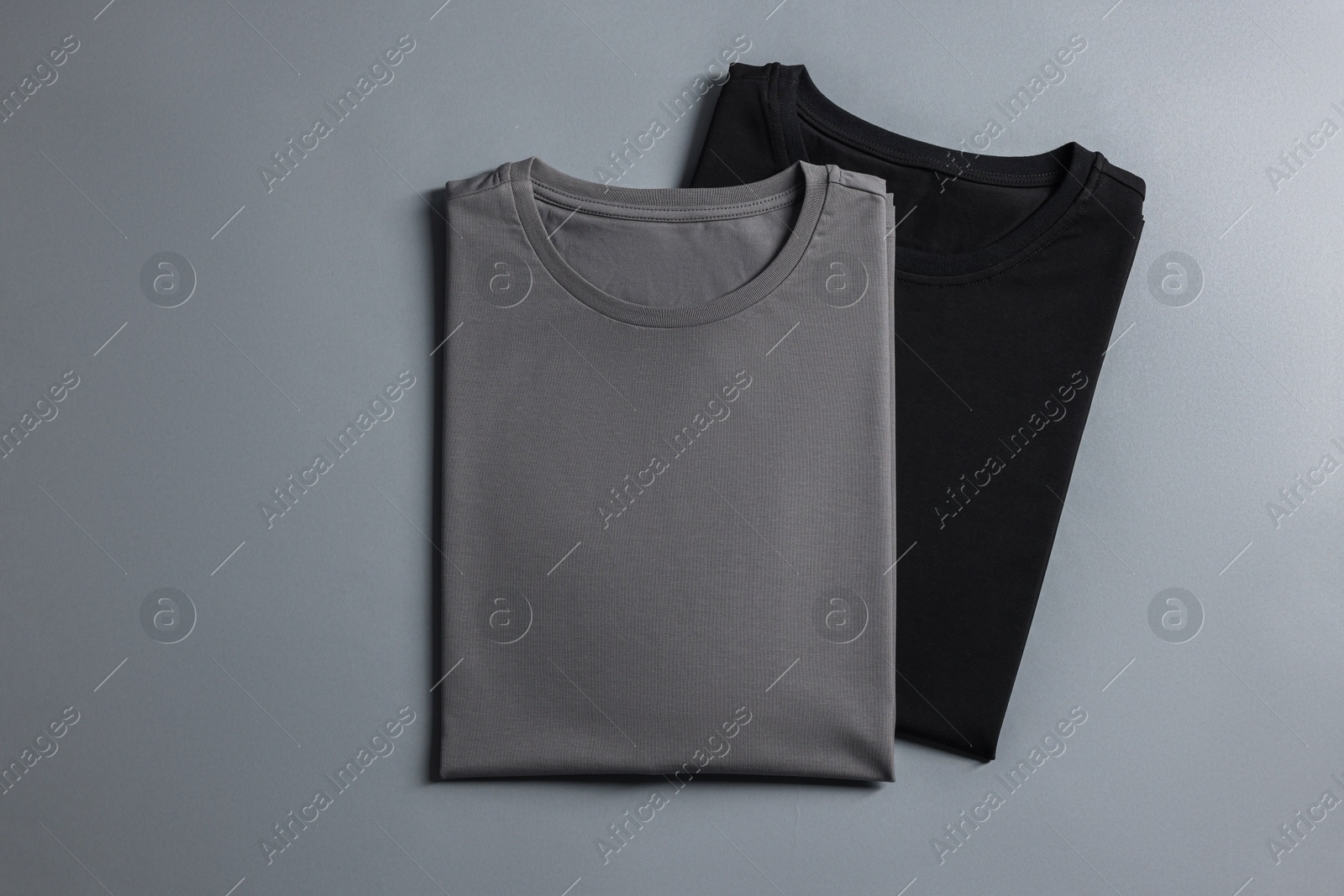 Photo of Different blank t-shirts on grey background, top view. Mockup for design