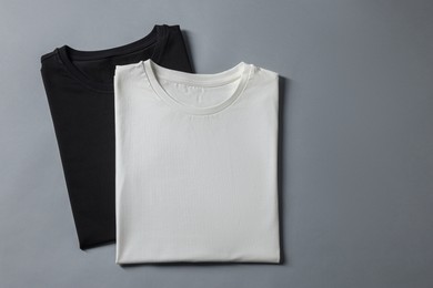 Different blank t-shirts on grey background, top view. Mockup for design