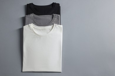 Photo of Different blank t-shirts on grey background, top view. Mockup for design