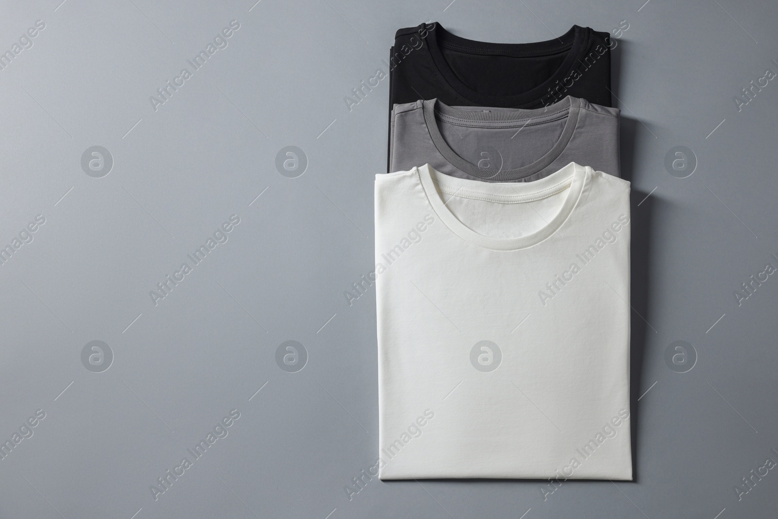 Photo of Different blank t-shirts on grey background, top view. Mockup for design