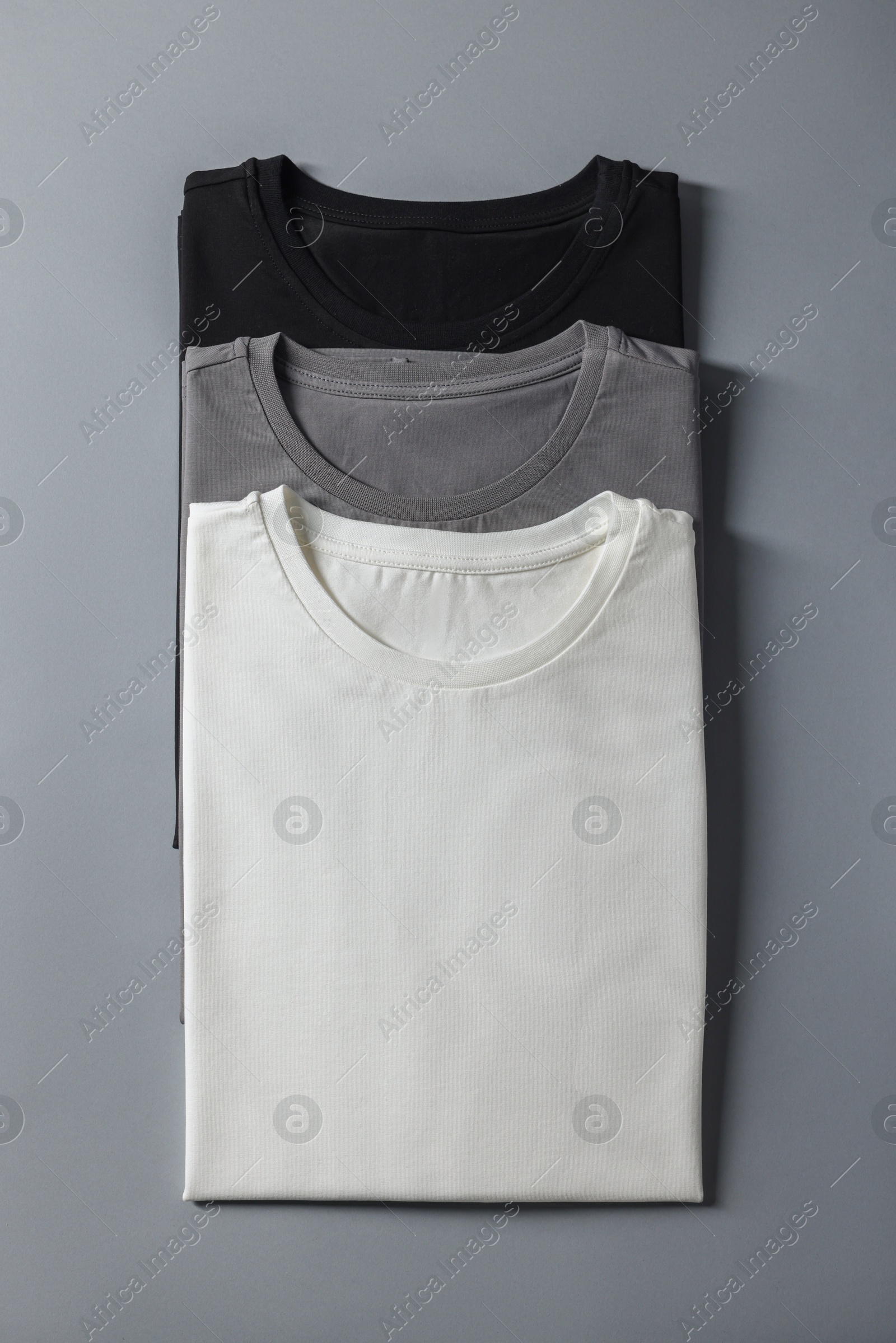 Photo of Different blank t-shirts on grey background, top view. Mockup for design