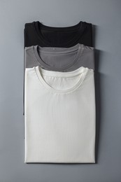 Photo of Different blank t-shirts on grey background, top view. Mockup for design