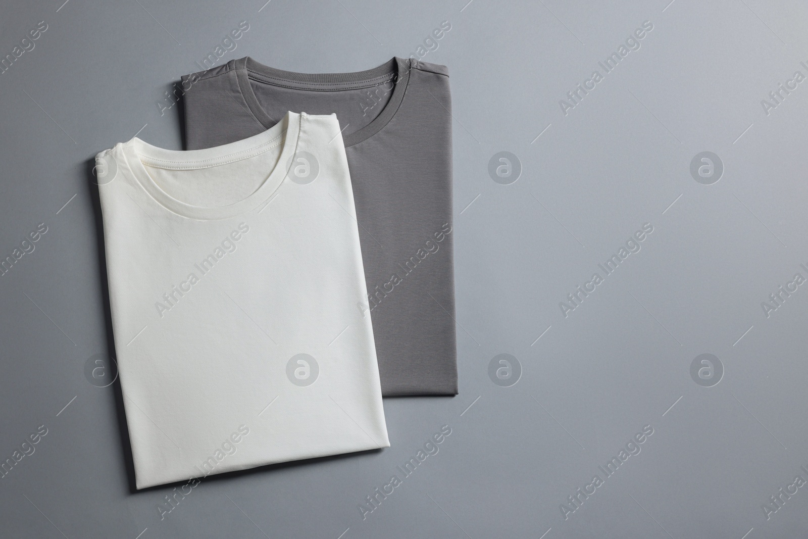 Photo of Different blank t-shirts on grey background, top view. Mockup for design