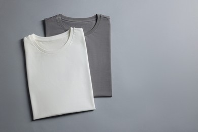 Photo of Different blank t-shirts on grey background, top view. Mockup for design