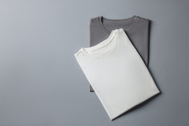 Photo of Different blank t-shirts on grey background, top view. Mockup for design