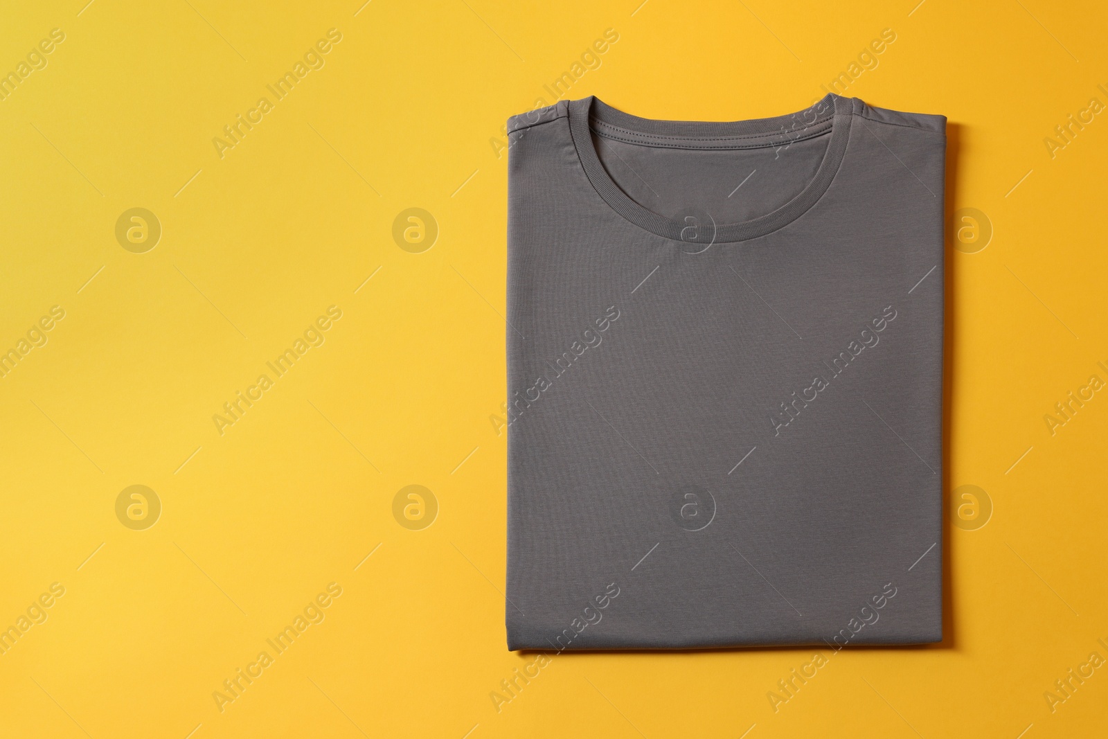 Photo of Blank grey t-shirt on yellow background, top view. Mockup for design