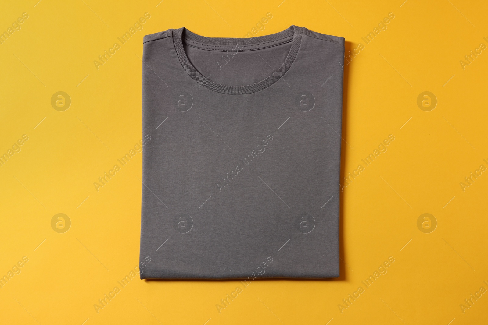 Photo of Blank grey t-shirt on yellow background, top view. Mockup for design