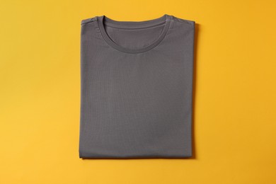 Photo of Blank grey t-shirt on yellow background, top view. Mockup for design