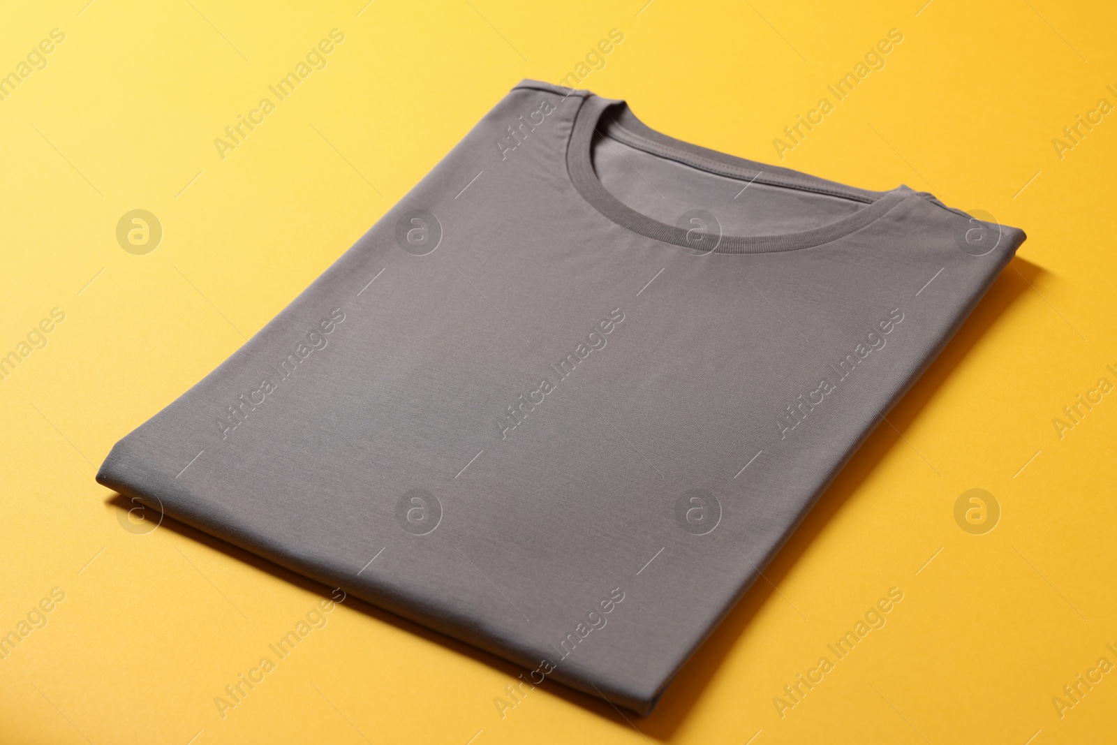 Photo of Blank grey t-shirt on yellow background. Mockup for design