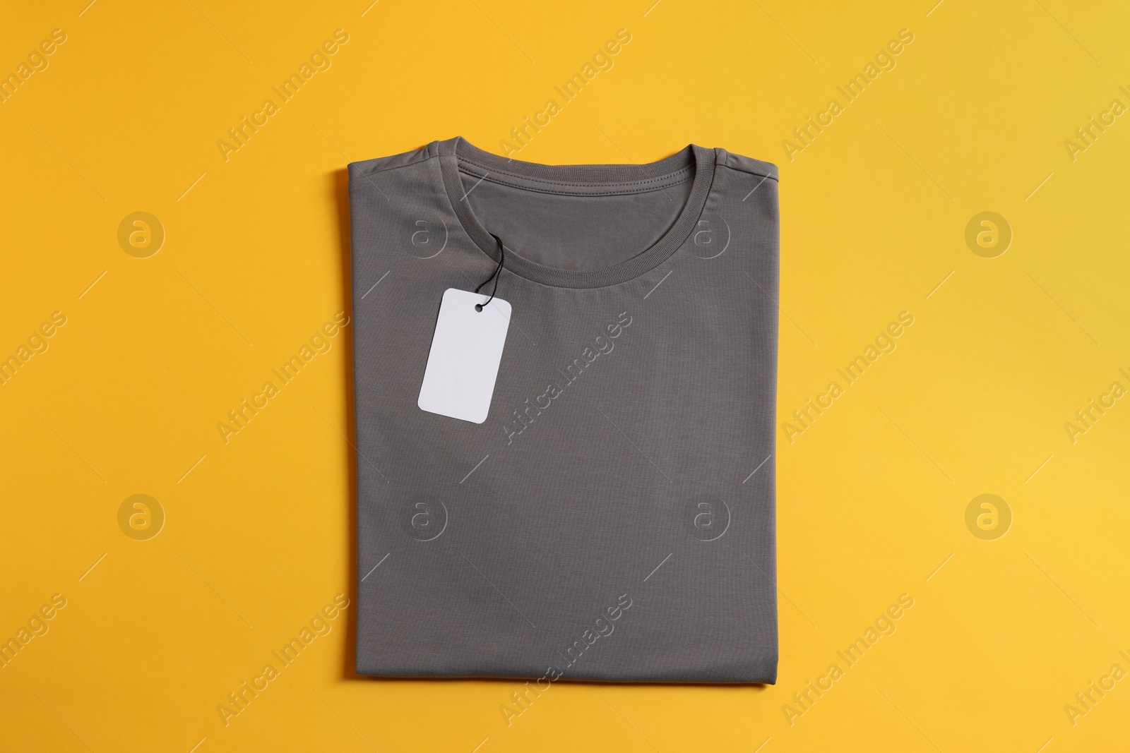 Photo of Blank grey t-shirt on yellow background, top view. Mockup for design