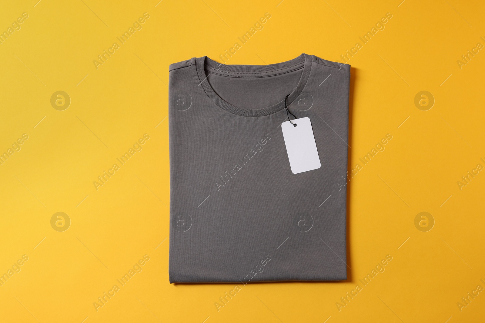 Photo of Blank grey t-shirt on yellow background, top view. Mockup for design