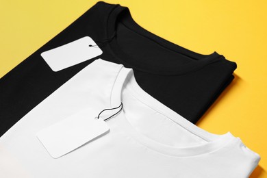 Photo of Different blank t-shirts on yellow background, closeup