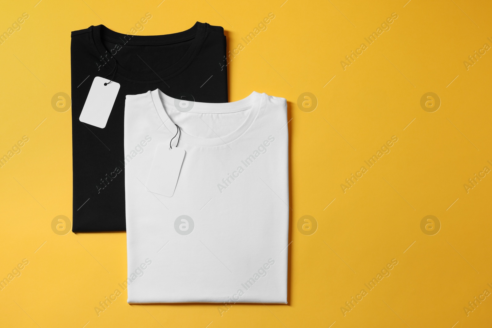 Photo of Different blank t-shirts on yellow background, top view. Mockup for design