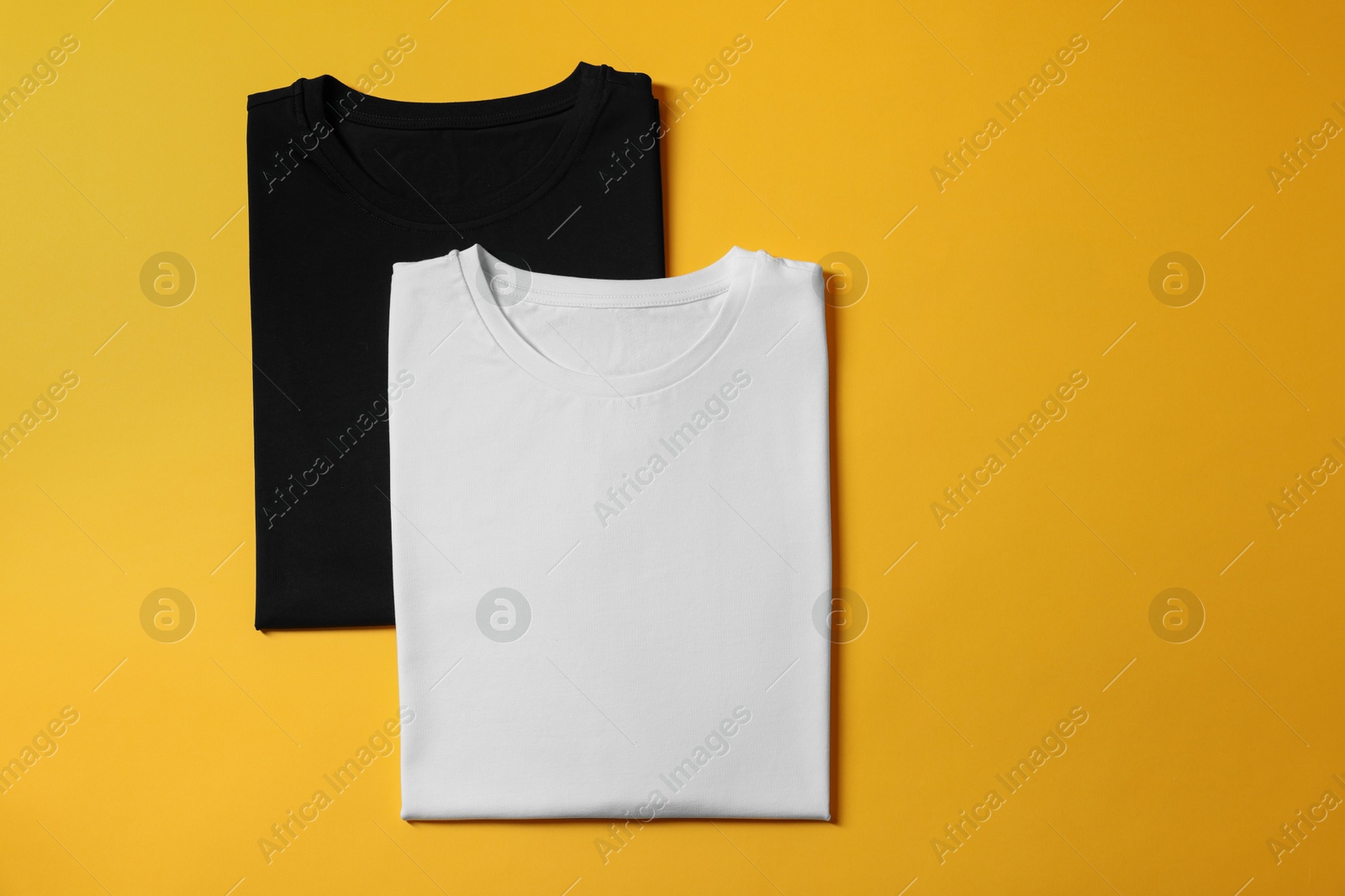 Photo of Different blank t-shirts on yellow background, top view. Mockup for design